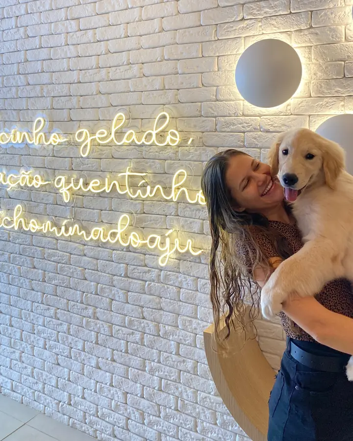 Filhote de golden no colo, em frente ao neon da recepção